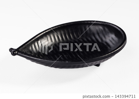 Black ceramic leaf shaped dish with ribbed texture and stem handle isolated on white background tableware Black ceramic leaf shaped dish with ribbed texture and stem handle isolated on white background tableware 143394711
