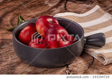 Still life of red flat nectarines in grey ceramic bowl on wooden surface, summer stone fruit 143394729