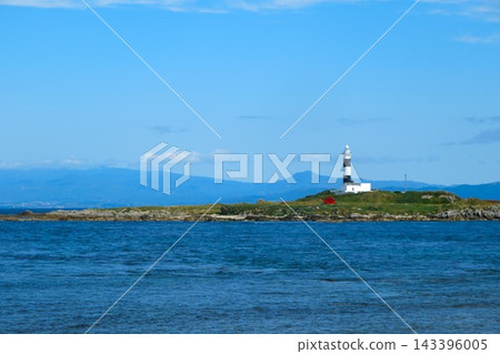 A white and black lighthouse standing in the sea A white and black lighthouse standing in the sea 143396005