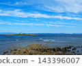 A lighthouse standing on a small island far from the shore 143396007