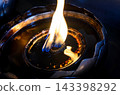 Close-up of a traditional oil lamp with a glowing flame in low light, symbolizing peace, spirituality, meditation, and hope 143398292