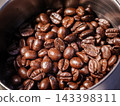 Close-up of freshly roasted coffee beans inside a coffee grinder hopper. Rich texture and aroma for espresso concept 143398311