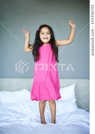 Energy, portrait and girl jumping on bed in morning for development, fun or growth in home. Bedroom, children and smile with excited little kid in apartment for action, joy or playful movement Energy, portrait and girl jumping on bed in morning for development, fun or growth in home. Bedroom, children and smile with excited little kid in apartment for action, joy or playful movement 143398705