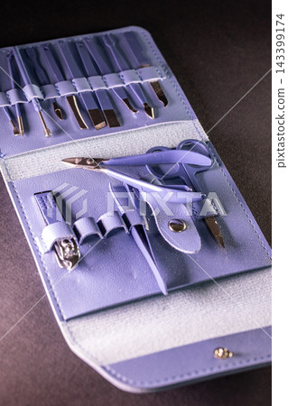 Lavender manicure set tools in open purple leather case on dark background vertical view Lavender manicure set tools in open purple leather case on dark background vertical view 143399174