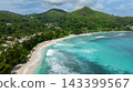 Clear turquoise waves wash over large smooth rocks on the white sandy shore, surrounded by greenery. Seychelles, Mahe. Baie Lazare. 143399567