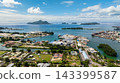 An industrial shipping port filled with containers, cranes, and cargo ships by the waterfront. Victoria. Seychelles, Mahe. 143399587