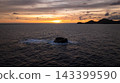 Distant islands form dark silhouettes against a sunset sky filled with warm hues. Seychelles, Mahe. 143399590