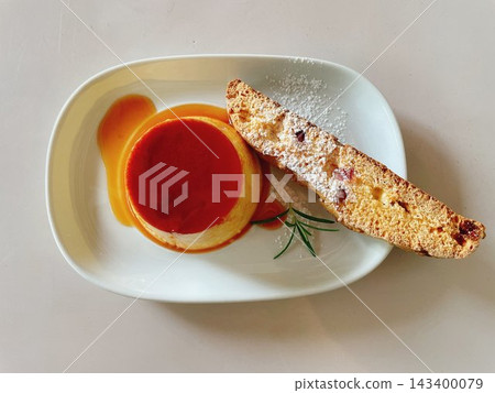 焦糖布丁和義式脆餅,一種用白色盤子盛裝的咖啡館甜點。 焦糖布丁和義式脆餅,一種用白色盤子盛裝的咖啡館甜點。 143400079
