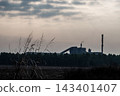 Factories and tall smokestacks stand alone amidst agricultural and wasteland areas 143401407