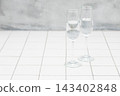 A stylish glass filled with water. White tiles. 143402848