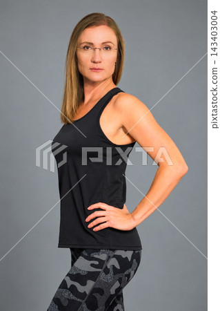 Confident female Pilates instructor in a relaxed professional pose, wearing a black sleeveless training top Confident female Pilates instructor in a relaxed professional pose, wearing a black sleeveless training top 143403004