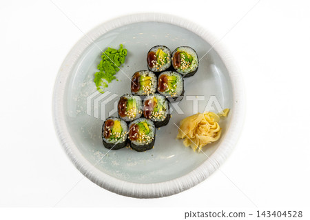 Avocado maki sushi rolls with unagi sauce and sesame, wasabi and pickled ginger on white plate, top view, white background Avocado maki sushi rolls with unagi sauce and sesame, wasabi and pickled ginger on white plate, top view, white background 143404528