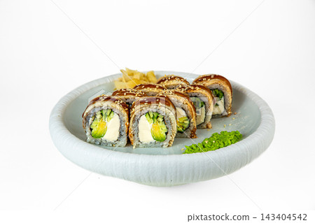 Sushi roll topped with eel, unagi sauce and sesame, filled with cream cheese, avocado and cucumber on white plate, isolated on white background Sushi roll topped with eel, unagi sauce and sesame, filled with cream cheese, avocado and cucumber on white plate, isolated on white background 143404542
