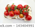 Cherry Tomato and Ricotta Bruschetta with Fresh Basil Garnish on White Plate 143404991