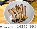 Empty Rib Bones in White Bowl on Wooden Table - Food Waste, Culinary, Restaurant Setting 143404998