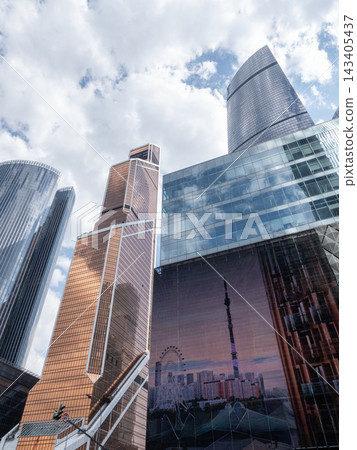 Modern glass skyscrapers with reflective facades rising against a clear blue sky in an urban setting 143405437