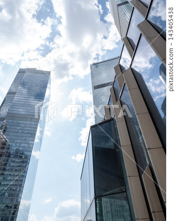 Modern glass skyscrapers with reflective facades rising against a clear blue sky in an urban setting Modern glass skyscrapers with reflective facades rising against a clear blue sky in an urban setting 143405438
