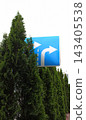 Green Hedge of Untrimmed Trees Blocks Road Sign with Right Turn Arrows in front of Crossroad 143405538