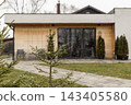 Snowfall on small conifer tree in front of modern house 143405580