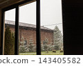 Snow falling on house seen through window frame 143405582