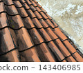 Clay roof tiles with a weathered texture and a wall 143406985