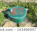 Round septic tank with ventilation amidst weeds 143406997