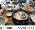 一道韓國料理，湯汁混濁，配上雞肉和小菜。 143407543