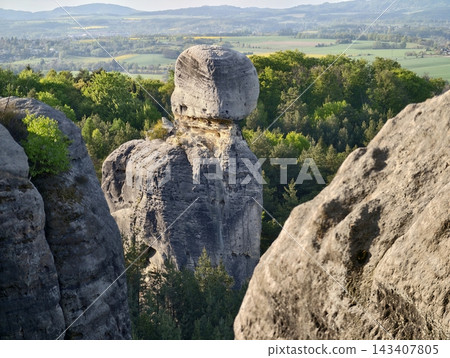 Cliffside monument with lush surroundings visible. Tall sandstone column emerges amidst green valley scenery Cliffside monument with lush surroundings visible. Tall sandstone column emerges amidst green valley scenery 143407805