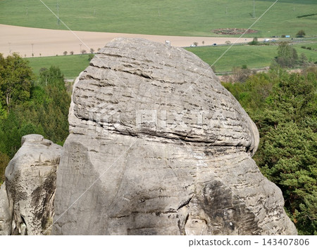 Weathered stone amid farmland view. Ancient massive rock overlooking scenic fields and meadows Weathered stone amid farmland view. Ancient massive rock overlooking scenic fields and meadows 143407806