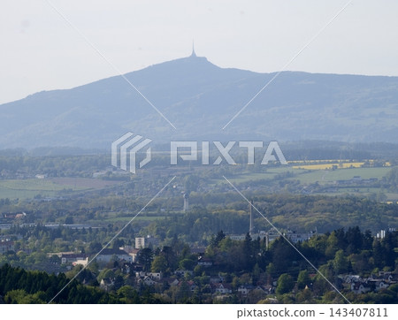 Peak towering above village and fields. High mountain casting shadows over town and farmlands below Peak towering above village and fields. High mountain casting shadows over town and farmlands below 143407811