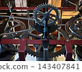 Old gears rotate. Historical mechanical gears in workspace illuminated by warm light and rich textures 143407841