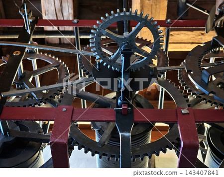 Old gears rotate. Historical mechanical gears in workspace illuminated by warm light and rich textures Old gears rotate. Historical mechanical gears in workspace illuminated by warm light and rich textures 143407841