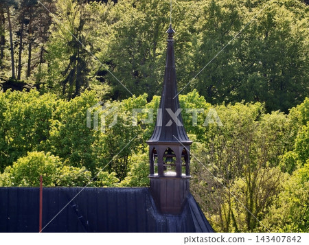 Church tower scenery. Mosscovered belfry exudes rustic charm within peaceful village landscape Church tower scenery. Mosscovered belfry exudes rustic charm within peaceful village landscape 143407842
