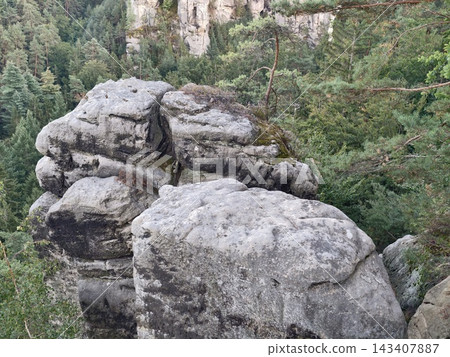 Large granite boulders amid pine forest on rugged cliff edge with mossy rock surfaces and natural stone outcrop, with rock, boulder, granite, outcrop detail, showing cliffside, cliff, ledge, forest Large granite boulders amid pine forest on rugged cliff edge with mossy rock surfaces and natural stone outcrop, with rock, boulder, granite, outcrop detail, showing cliffside, cliff, ledge, forest 143407887