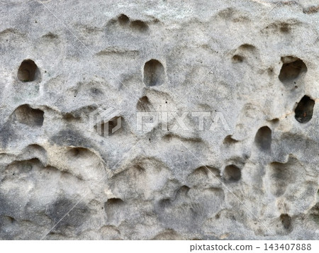 Close up view of weathered stone surface with holes and pitted texture showing erosion patterns and natural tonal variation, with stone, rock, surface, texture detail Close up view of weathered stone surface with holes and pitted texture showing erosion patterns and natural tonal variation, with stone, rock, surface, texture detail 143407888