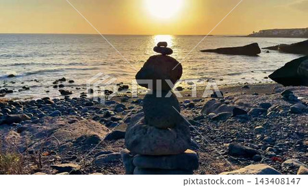A Serene Sunset Featuring Beautifully Balanced Stones Gracefully Placed on a Tranquil Beach Setting 143408147
