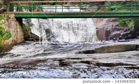 A Serene Waterfall Cascading Gently Under a Charming Bridge amidst Natural Surroundings 143408305