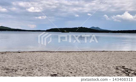 Serene Beach View Featuring Calm Waters and an Overcast Sky Perfect for Relaxation Serene Beach View Featuring Calm Waters and an Overcast Sky Perfect for Relaxation 143408313