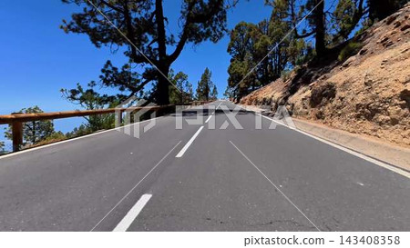 A scenic and beautiful mountain road, surrounded by lush green pines under clear blue skies A scenic and beautiful mountain road, surrounded by lush green pines under clear blue skies 143408358