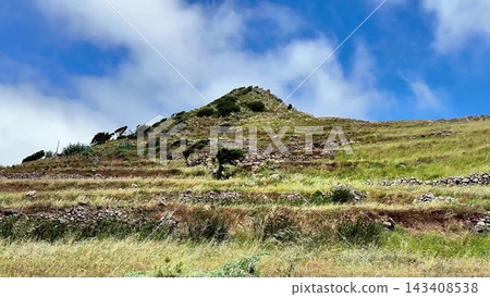 A beautiful, scenic hill with lush terraced fields sits under a vibrant, clear blue sky A beautiful, scenic hill with lush terraced fields sits under a vibrant, clear blue sky 143408538