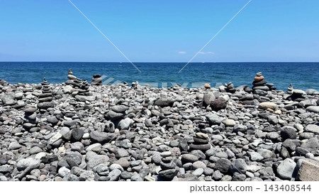 Beautifully arranged, peaceful stacked stones by the tranquil sea under a clear blue sky Beautifully arranged, peaceful stacked stones by the tranquil sea under a clear blue sky 143408544