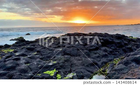 A Vibrant Sunset Over a Rocky Shoreline Capturing Natures Stunning Beauty and Serenity 143408614