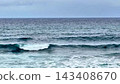 Surfers skillfully riding the impressive waves on a cloudy day at the stunning ocean 143408670