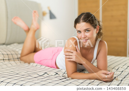Young woman posing on bed in bedroom Young woman posing on bed in bedroom 143408850