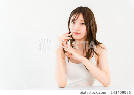 一位年輕女子手撫臉頰，展現出光滑的肌膚和自然的妝容，是一張非常美麗的照片。 143409956