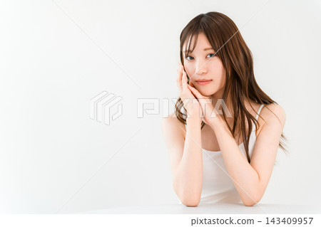 一位年輕女子手撫臉頰,展現出光滑的肌膚和自然的妝容,是一張非常美麗的照片。 一位年輕女子手撫臉頰,展現出光滑的肌膚和自然的妝容,是一張非常美麗的照片。 143409957