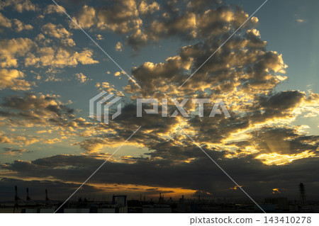 夕陽西下,工業區輪廓清晰可見;陽光穿透雲層,展現日本的城市景觀;背景素材留有文字空間。 夕陽西下,工業區輪廓清晰可見;陽光穿透雲層,展現日本的城市景觀;背景素材留有文字空間。 143410278