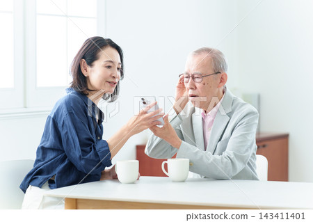 一位聽力障礙的老人正在接受智慧型手機使用說明。 一位聽力障礙的老人正在接受智慧型手機使用說明。 143411401