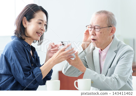 一位聽力障礙的老人正在接受智慧型手機使用說明。 一位聽力障礙的老人正在接受智慧型手機使用說明。 143411402