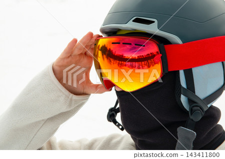 Ski. Skier prepares for a day on the slopes, adjusting vibrant goggles Ski. Skier prepares for a day on the slopes, adjusting vibrant goggles 143411800